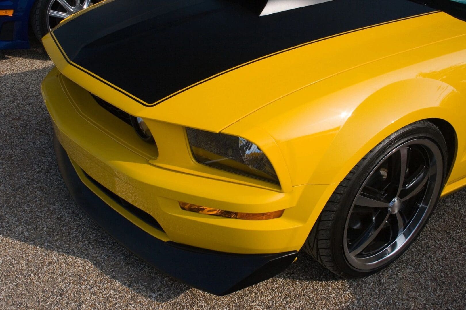 A close up of the front end of a yellow car